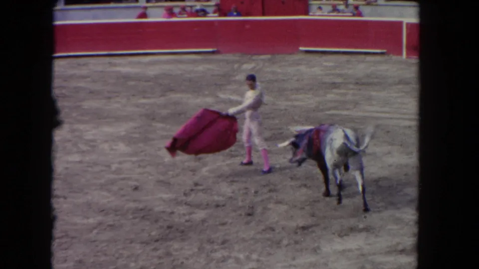 1962 Los Angeles 8mm frame with a matador extending a red cape toward a bull in the ring.