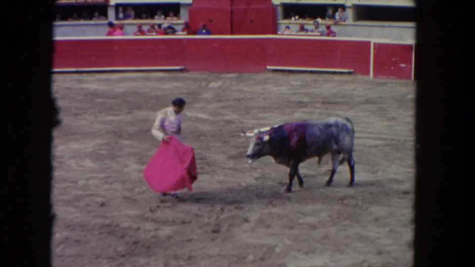 Vintage 8mm frame from Los Angeles in 1962 showing a matador extending a red cape as a bull passes nearby.