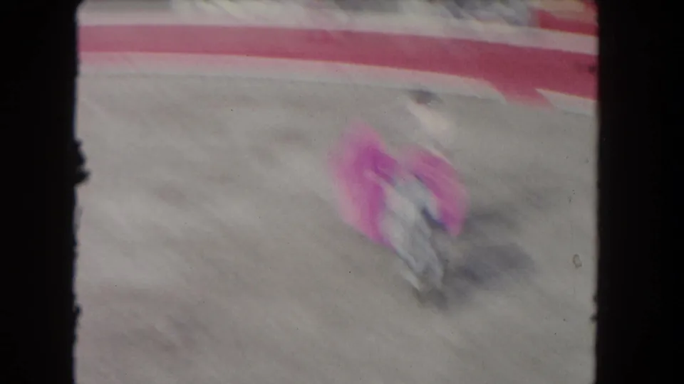 Motion-blurred 1962 Los Angeles 8mm frame of the matador, pink cape, and grey bull moving across the arena.