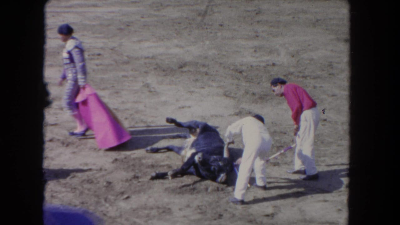 1962 Los Angeles 8mm frame with a bull down in the arena while handlers move in with poles and a cape.
