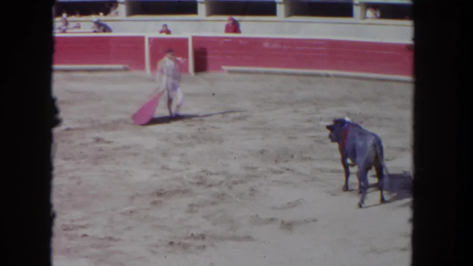 1962 Los Angeles arena frame with a matador carrying a red cape as the bull stands apart near the lower edge of the ring.