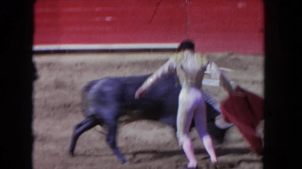1962 Los Angeles 8mm frame showing the matador beside the bull after a close pass in the dirt arena.