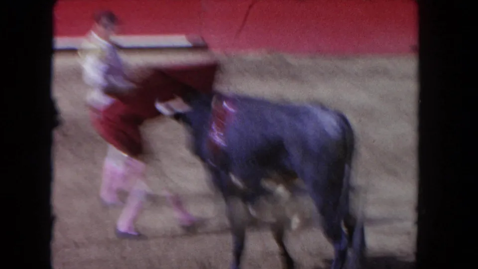 1962 Los Angeles 8mm frame showing a blurred cape turn with the bull alongside in the arena.