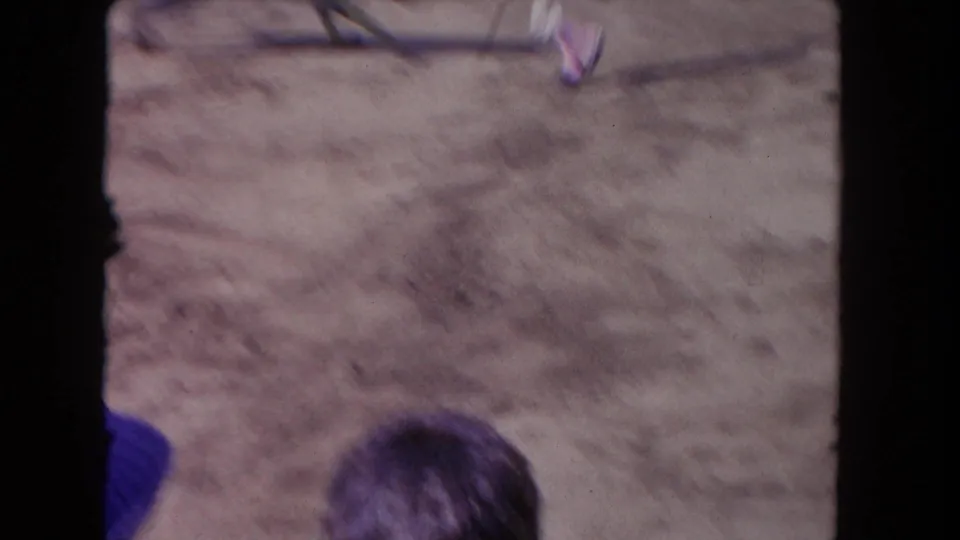 1962 Los Angeles 8mm frame blurs across the arena floor, with spectator heads and partial action at the edge.