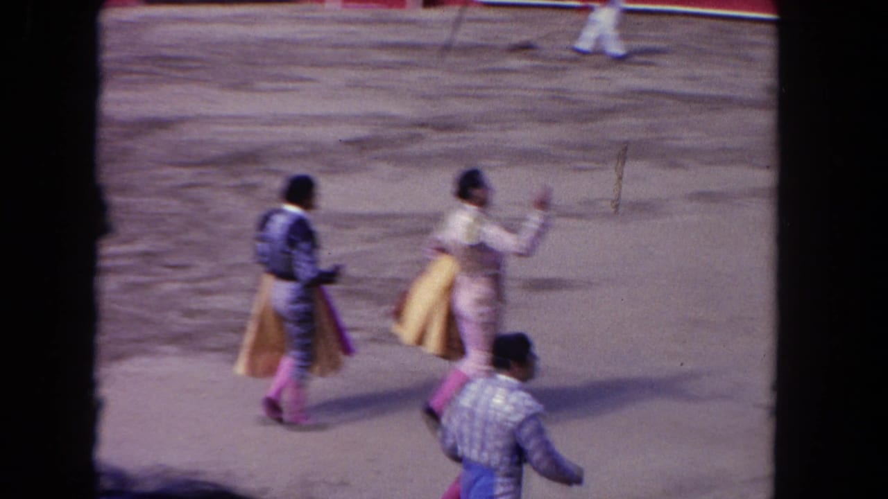 Two matadors walk along the arena floor while another figure moves near the lower edge.