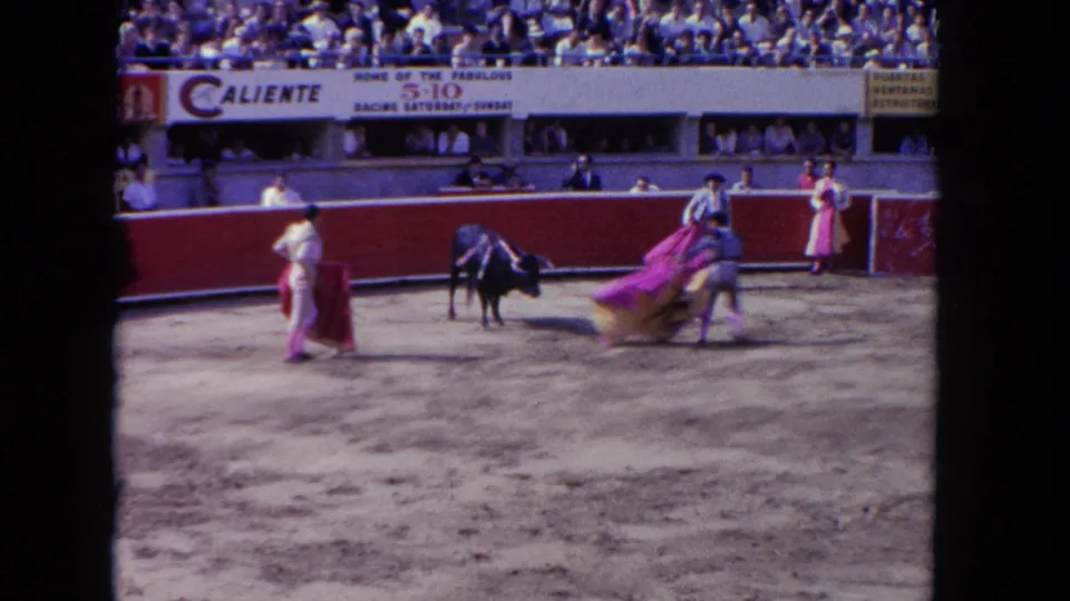 1962 Los Angeles frame showing matadors crossing the sandy arena with pink capes while a dark bull remains nearby.