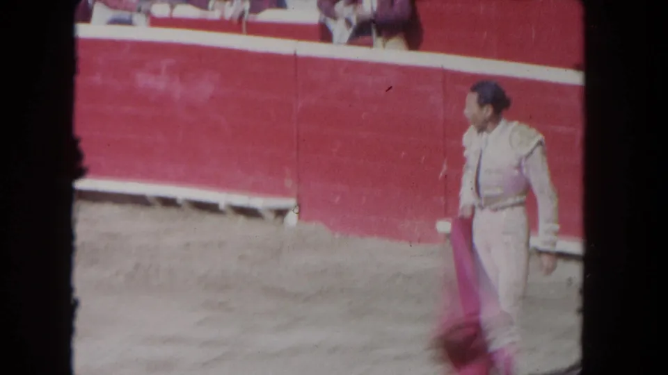 1962 Los Angeles 8mm frame showing the matador walking beside the red arena barrier with the cape lowered.