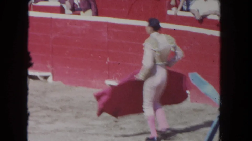 1962 Los Angeles frame with the matador seen from behind, moving a red cape near the red arena wall.