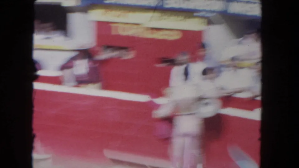 Motion-blurred 8mm frame from the Los Angeles arena as the camera follows matador and bull movement along the red barrier.
