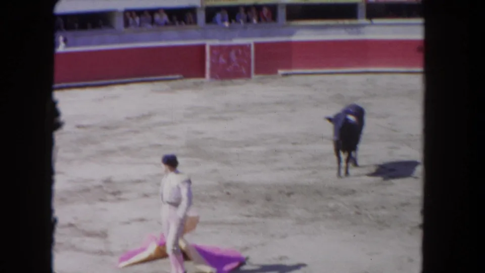 A matador carries the pink and yellow cape while the black bull stands at a distance in the 1962 Los Angeles arena scene.