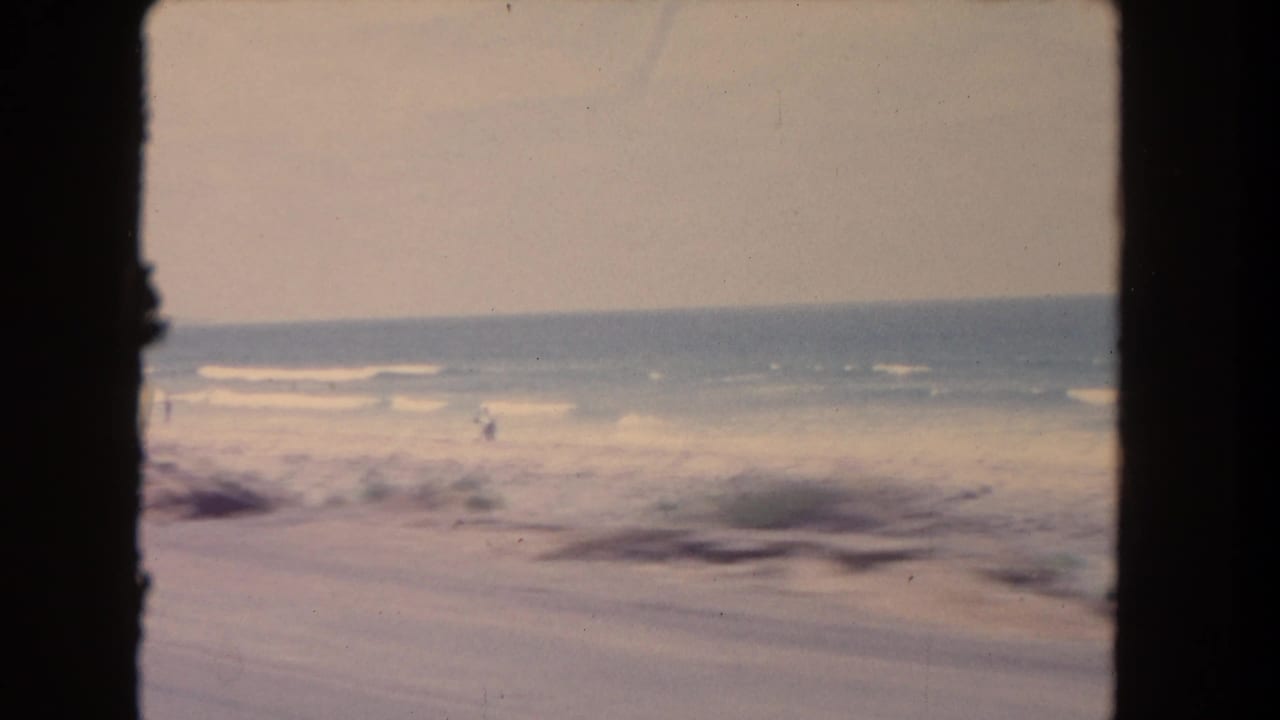 Distant beach and surf seen through an 8mm film frame.