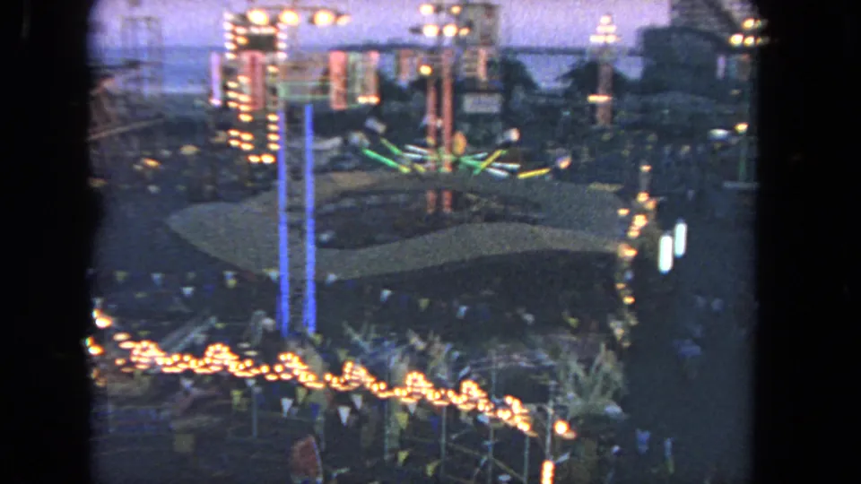 Final 1962 Los Angeles Ferris wheel view over illuminated amusement rides, green neon accents, bunting, palms, and visitors at dusk.