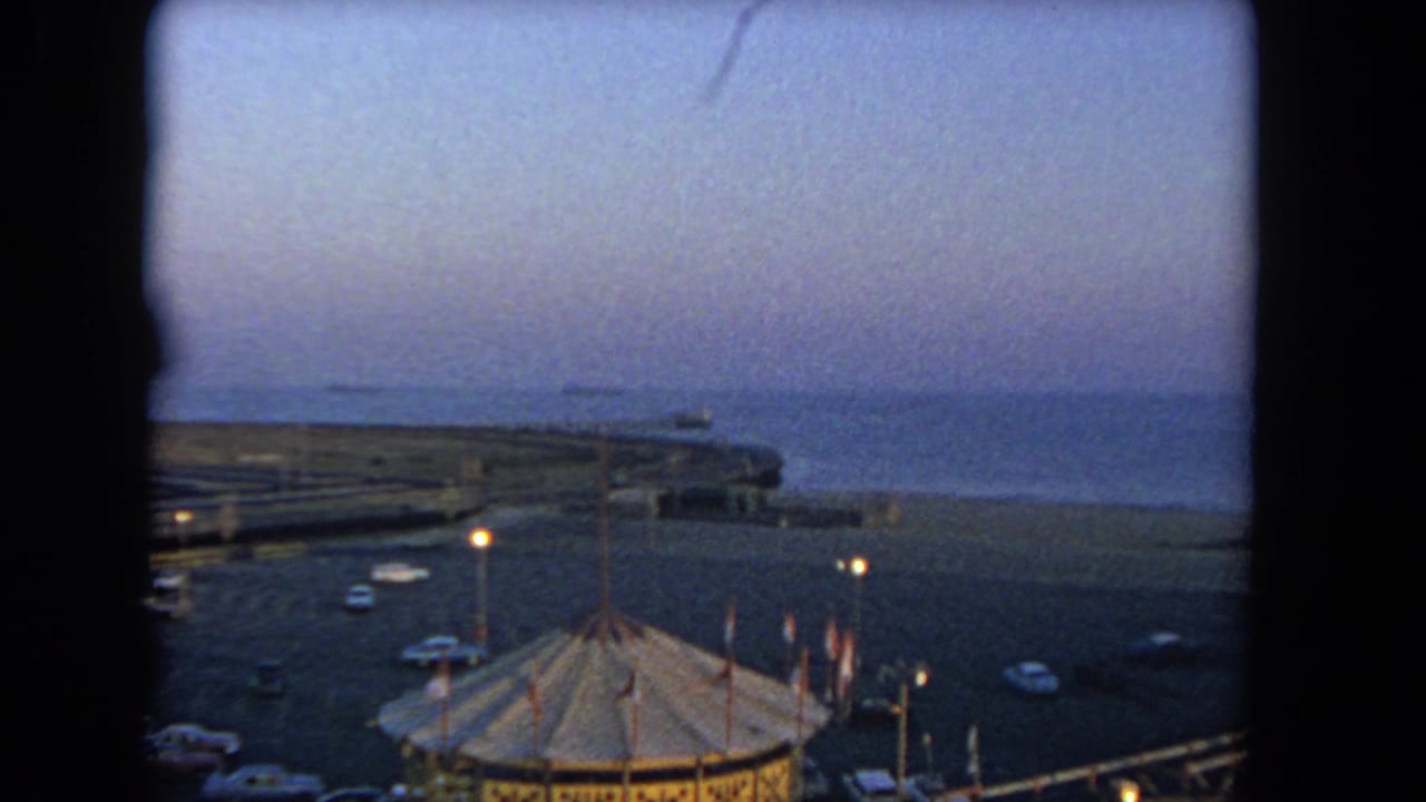 Carousel roof and waterfront parking lot seen against a dim ocean horizon.