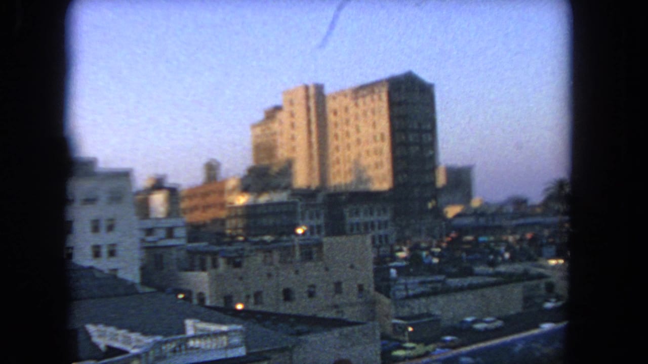 Los Angeles city buildings at dusk, with parked cars below and soft 8mm color and focus.