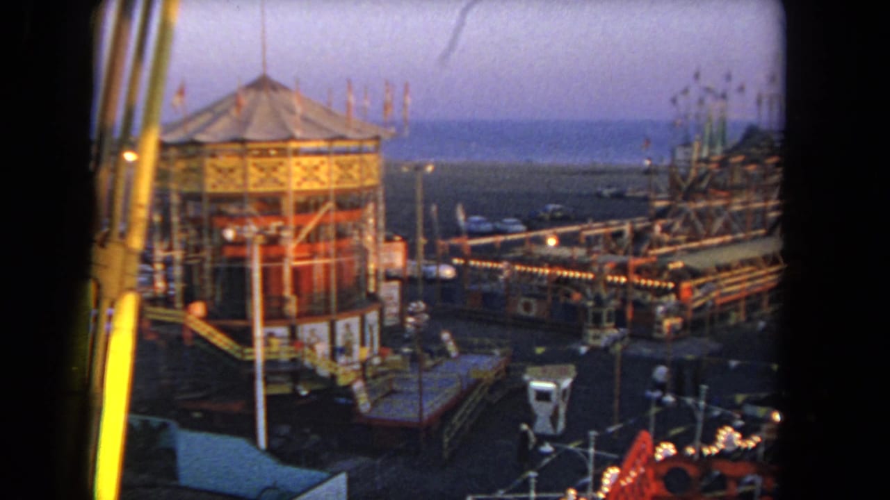 Domed fairground structure seen from above with ride framework and lights at dusk.