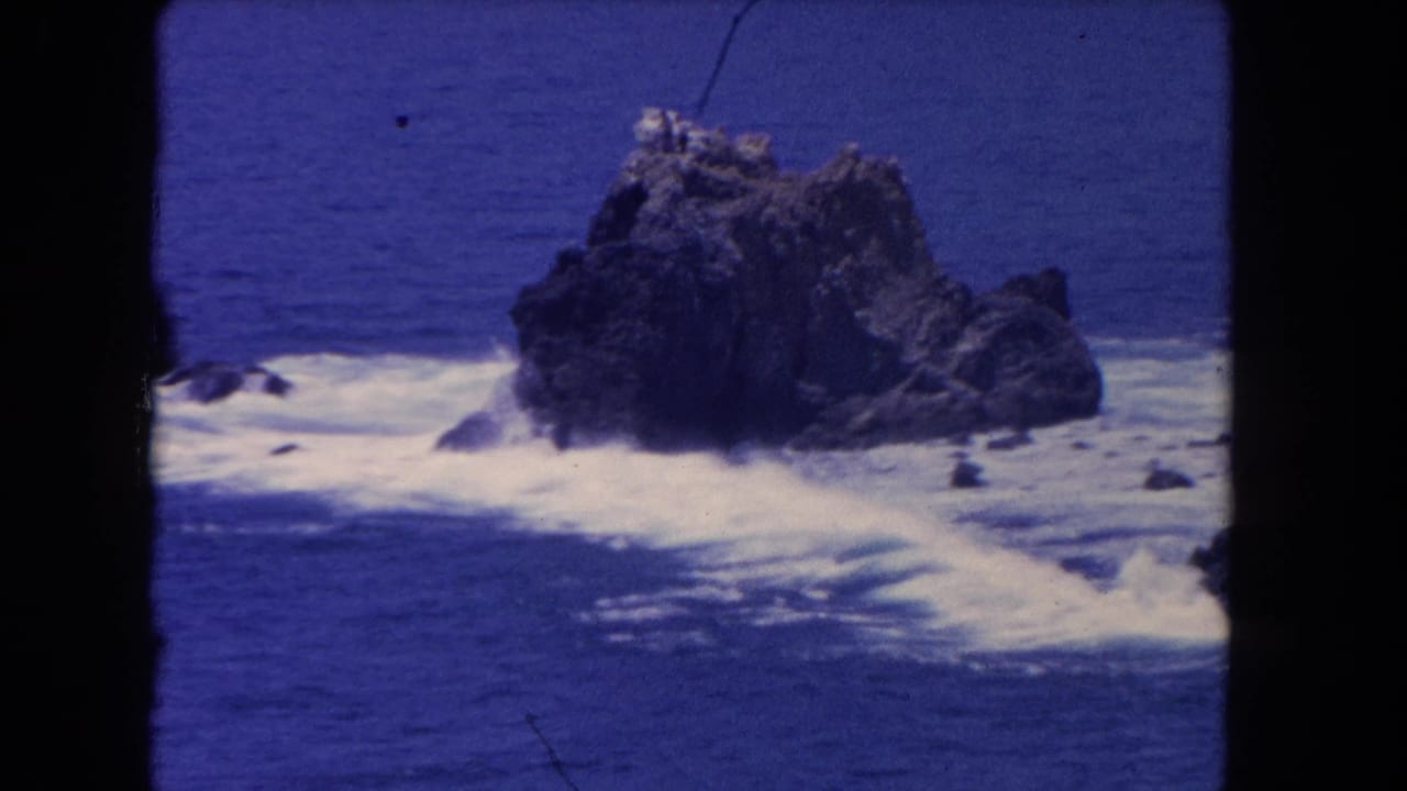Ocean waves curling around a rugged rock formation.