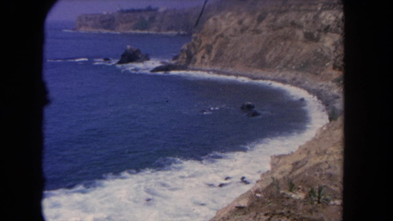 1962 Los Angeles coastal view from above, showing blue water, steep cliffs, white surf, and scattered rocks offshore.