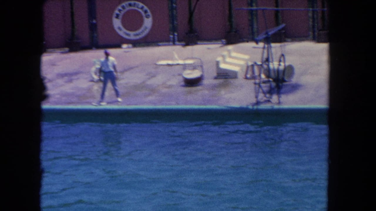1962 Los Angeles aquarium show view with a trainer on the deck, blue tank water, and a Sea World of the Pacific life ring visible behind.