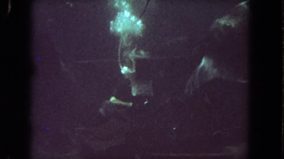 1962 8mm underwater footage from Los Angeles showing murky water, dim green light, and indistinct diving forms.