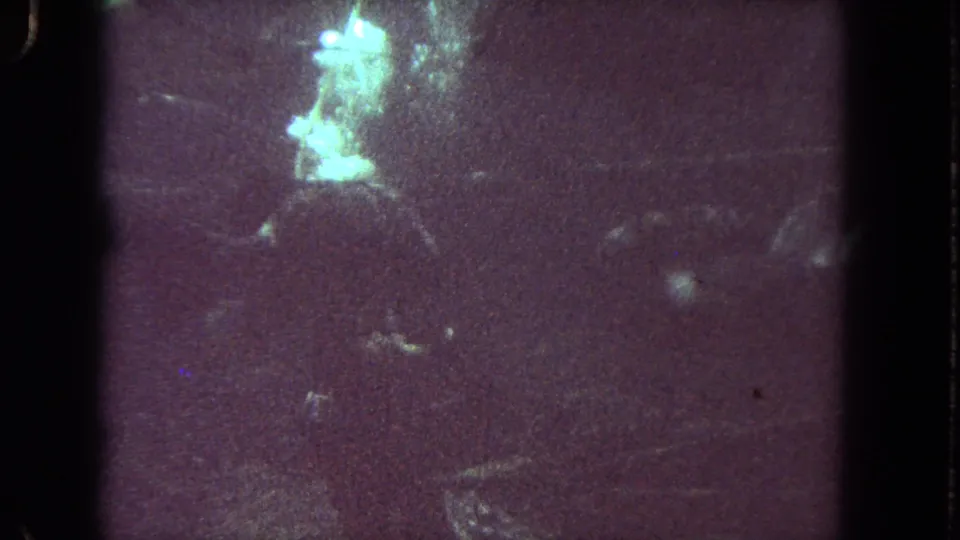 Los Angeles 1962 home-movie underwater frame with a bright greenish glow and indistinct scuba-related shapes.