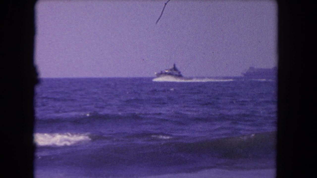 Distant speedboat crosses the ocean near the horizon behind rolling surf.