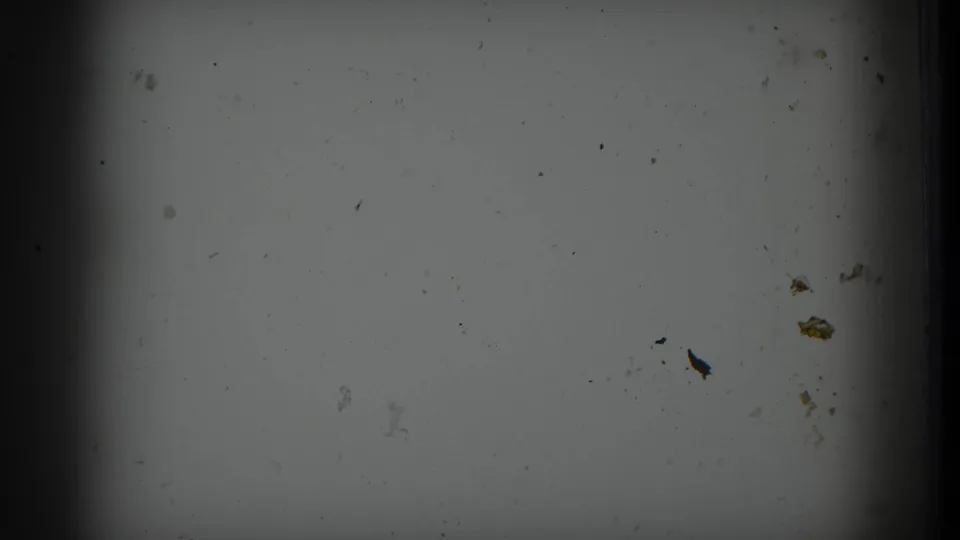 Blank or overexposed leader frame at clip start showing scattered debris and emulsion staining typical of aged 8mm home-movie film stock.