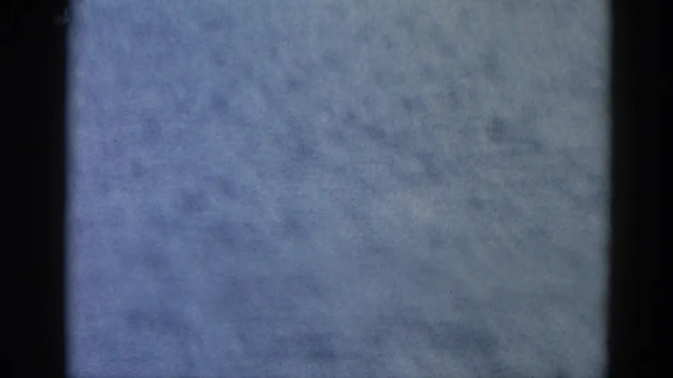 Opening frame from an 8mm home movie shot circa 1962 in Illinois; heavy underexposure reveals only overcast sky texture and film grain.