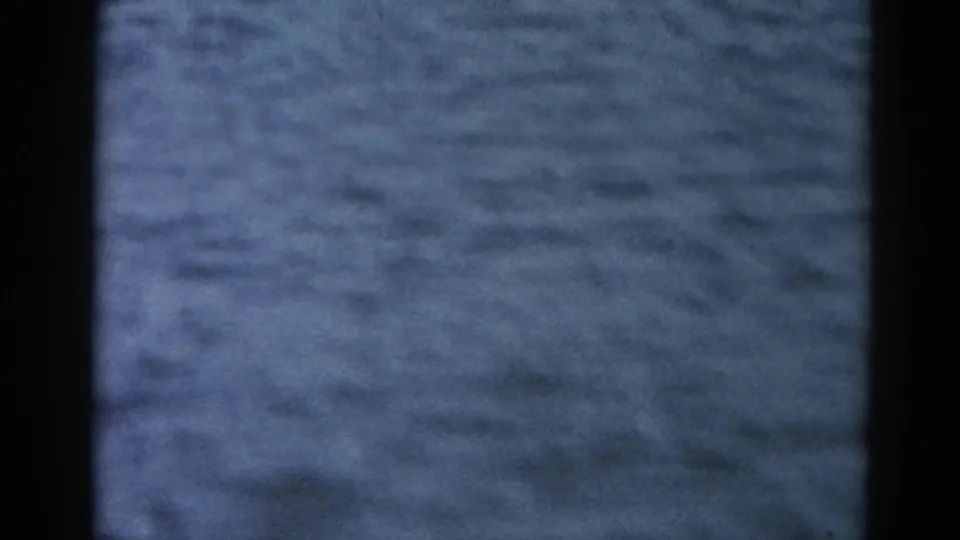 Close-up 8mm home movie frame showing a textured Midwest river surface with faded blue-grey color typical of early-1960s film stock, no subjects visible.