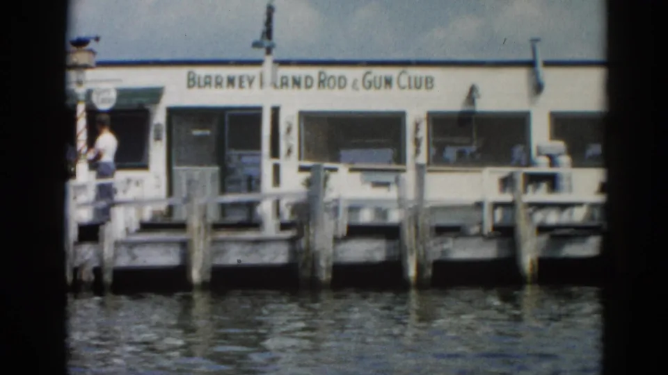 'Blarney Island Rod & Gun Club' white building at an Illinois waterfront dock, circa 1962; one adult figure standing near the dock entrance.