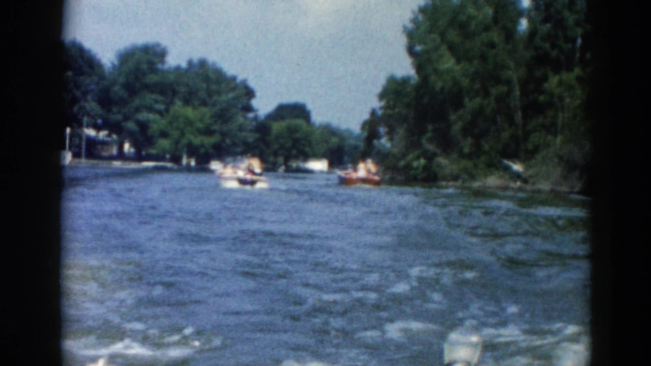 Continued 8mm river footage from 1962 Illinois showing motorboats at distance and dense tree canopy along both shorelines