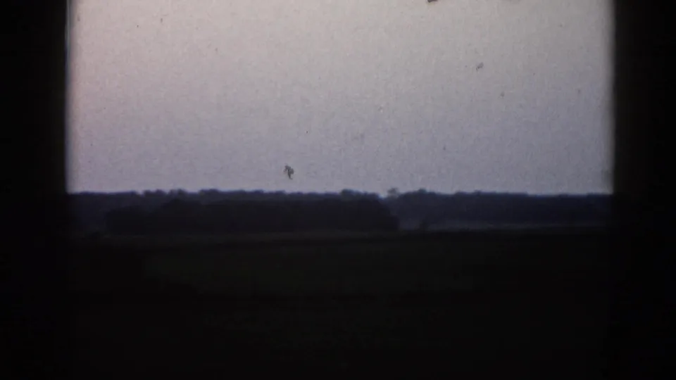 Severely overexposed or end-of-reel 8mm frame with a faint horizon line at the lower edge and near-white field throughout.