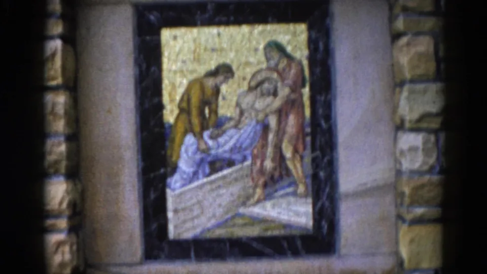 Final 8mm frame of the Deposition mosaic with slight handheld repositioning, same scene of robed figures over a stone slab on gold tesserae, Illinois church interior, circa 1962.