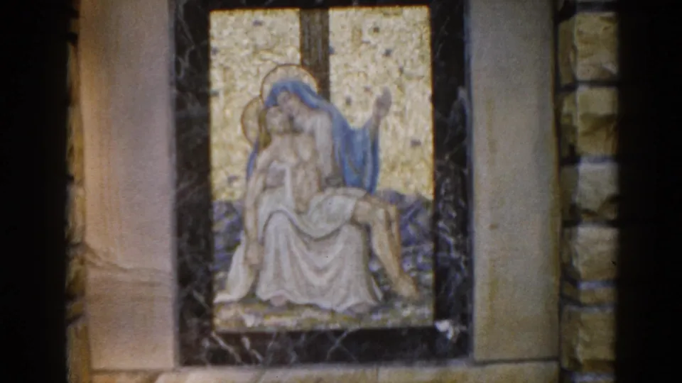 Opening 8mm frame from 1962 Illinois church footage: mosaic Pietà with blue-robed Virgin Mary cradling recumbent Christ against a golden tessera background.