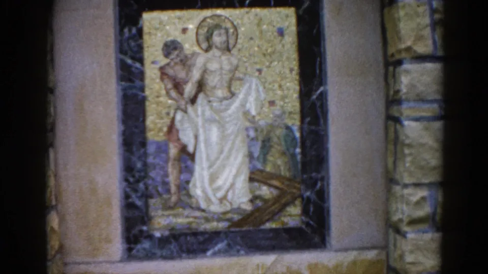 8mm film frame, 1962, Illinois: same mosaic panel with slight handheld camera drift to left, revealing more stone surround; gold tessellated background remains dominant.