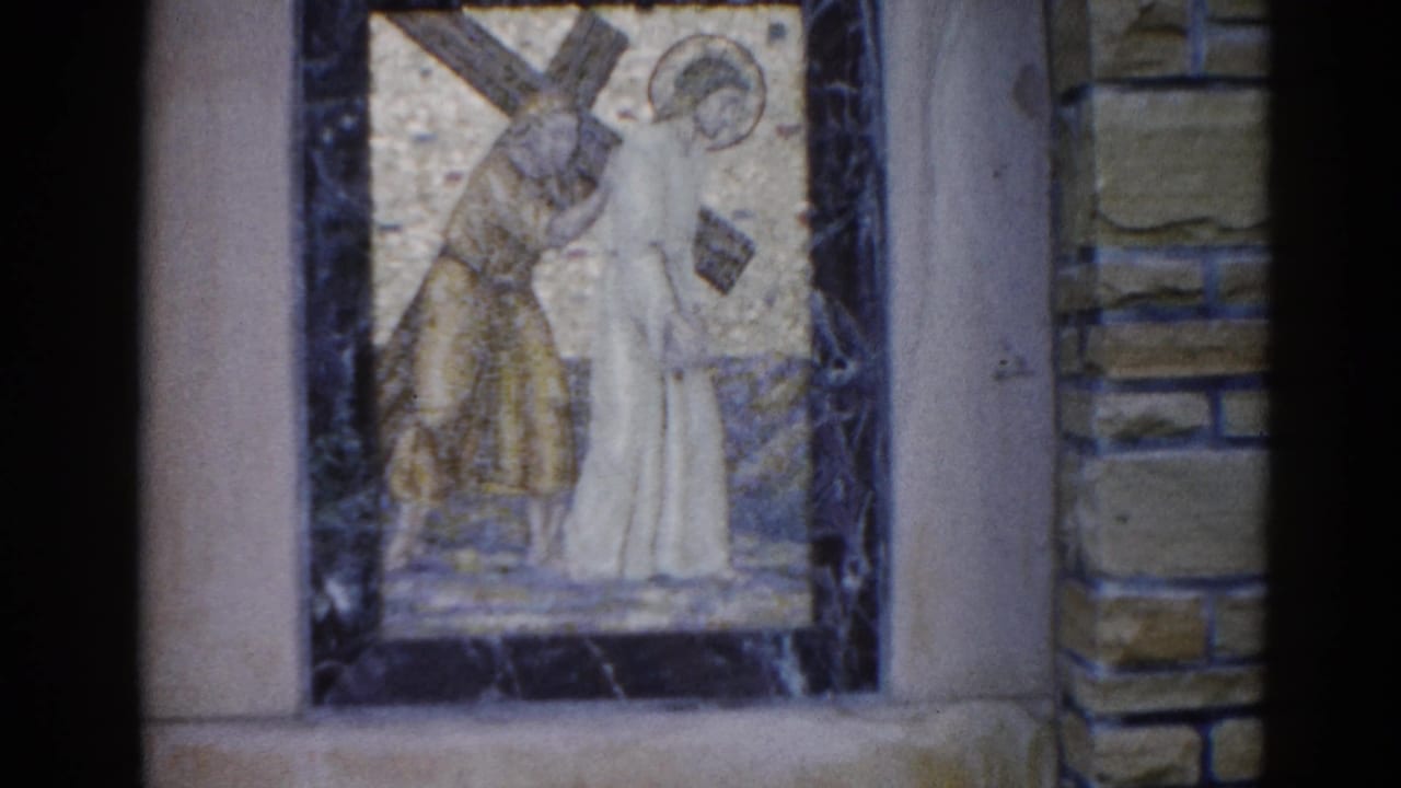 Church mosaic panel with two figures and diagonal cross, gold tessera background, dark marble frame, stone wall at edges.