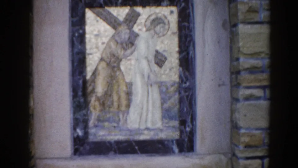1962 Illinois church mosaic: haloed figure bent under a large wooden cross with an accompanying robed figure, rendered in gold and white tesserae.