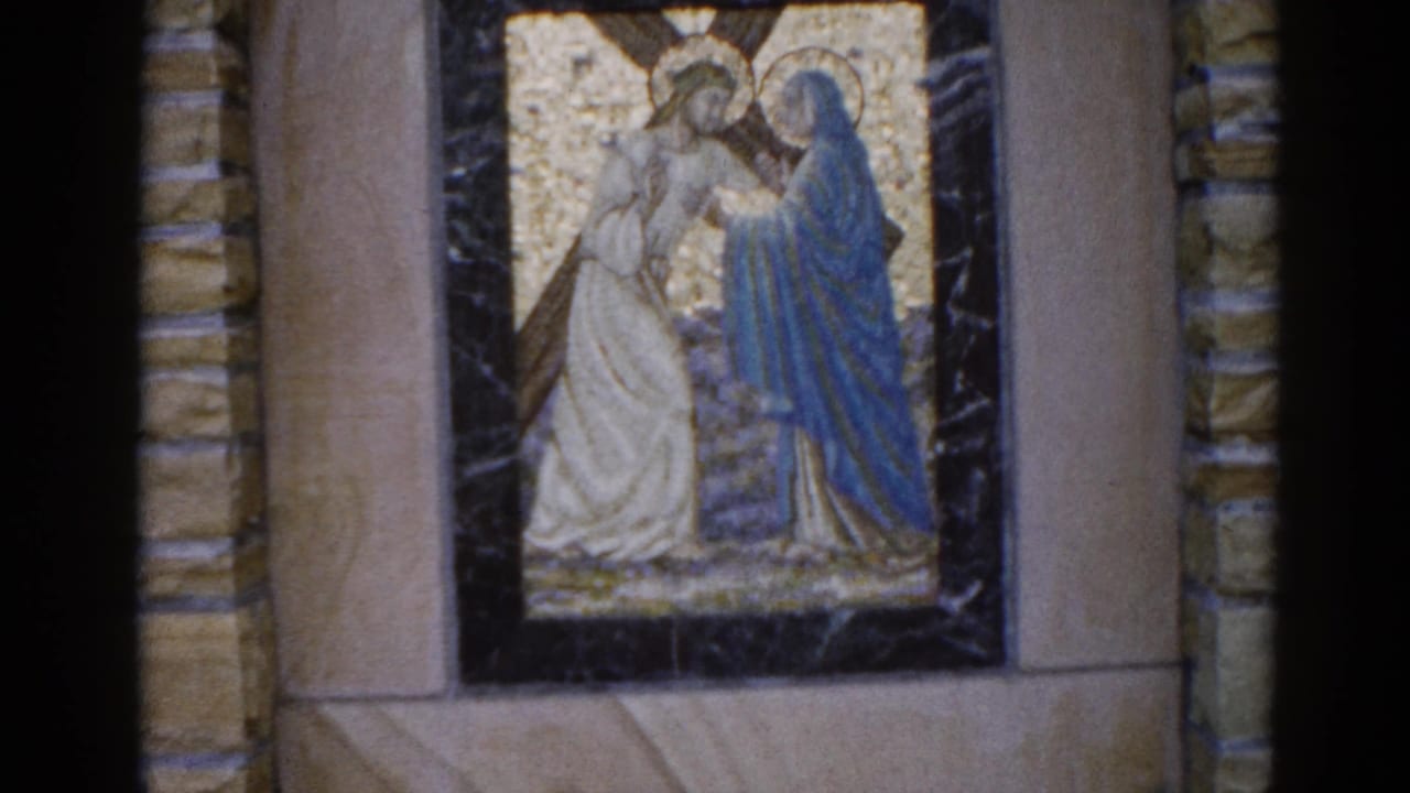 Second religious mosaic showing two haloed figures in white and blue robes on a gold background, framed in dark marble on a stone wall.