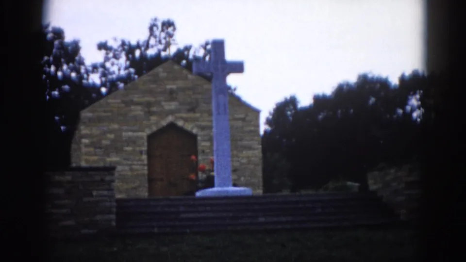 Illinois brick chapel exterior circa 1962, white cross centered before the arched door, cool-toned 8mm exposure with pronounced edge vignetting.