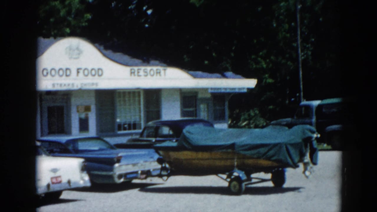 'GOOD FOOD RESORT' building from a near-identical angle to frame 0, fin-era cars and covered boat on trailer visible.