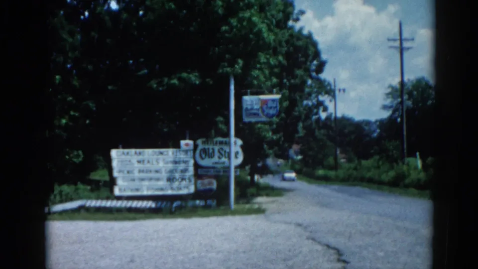 Illinois roadside circa 1962: resort amenity sign listing meals, rooms, boats, and bathing, alongside an apparent Old Style beer sign, utility pole, and summer foliage.