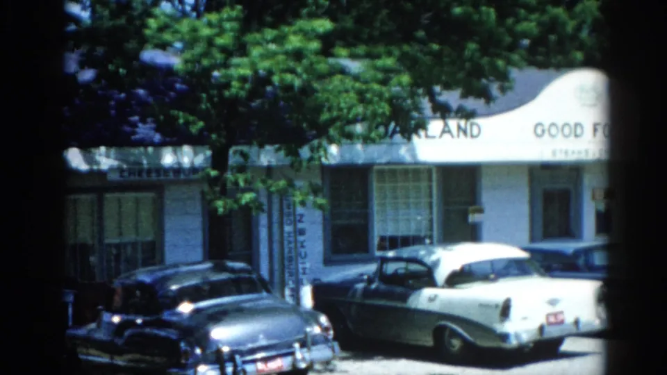 8mm home movie frame circa 1962, Illinois: 'Oakland Good Food Resort' building with late-1950s American sedans in the parking lot.