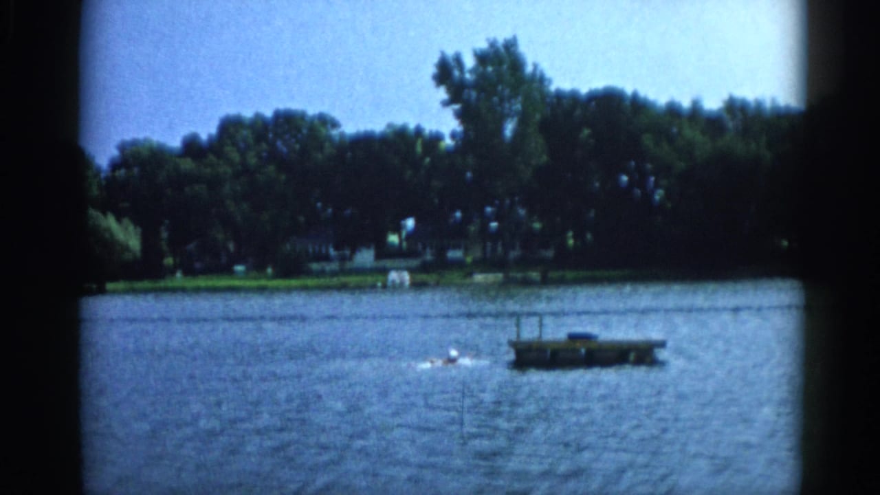 Swimmer approaching a floating wooden dock on a Midwest lake, 8mm home movie footage, Illinois circa 1962.