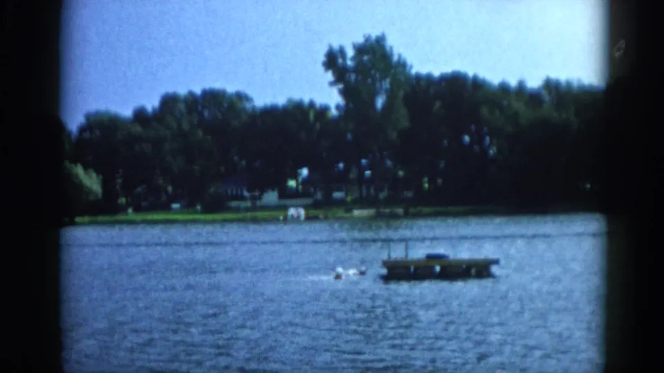 Floating dock with swimmers nearby on a sunlit Illinois lake, 8mm home movie, circa 1962.