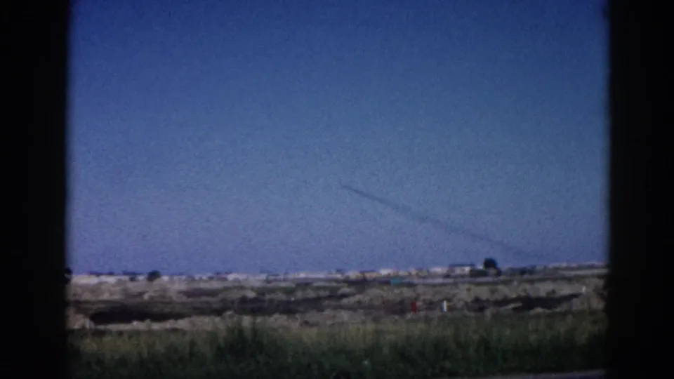 8mm home movie, 1962 Illinois — passenger window view of open prairie under deep blue sky, faint contrail crossing the upper frame