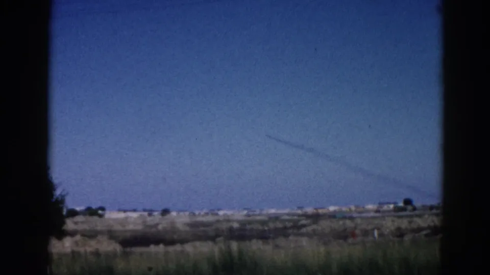8mm home movie, 1962 Illinois — sky fills most of the frame as the vehicle moves past low prairie terrain, contrail visible diagonally