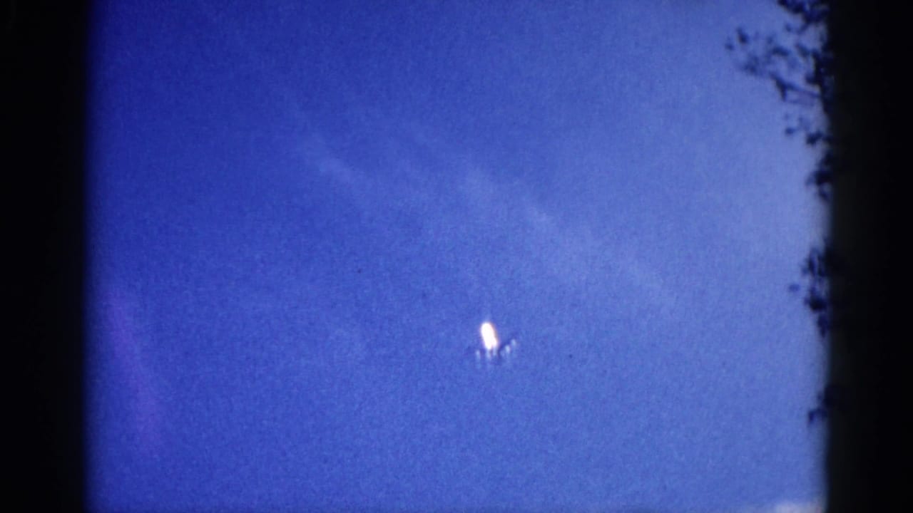 Jet aircraft as luminous white point in saturated blue sky, 8mm home movie, Illinois, circa 1962.