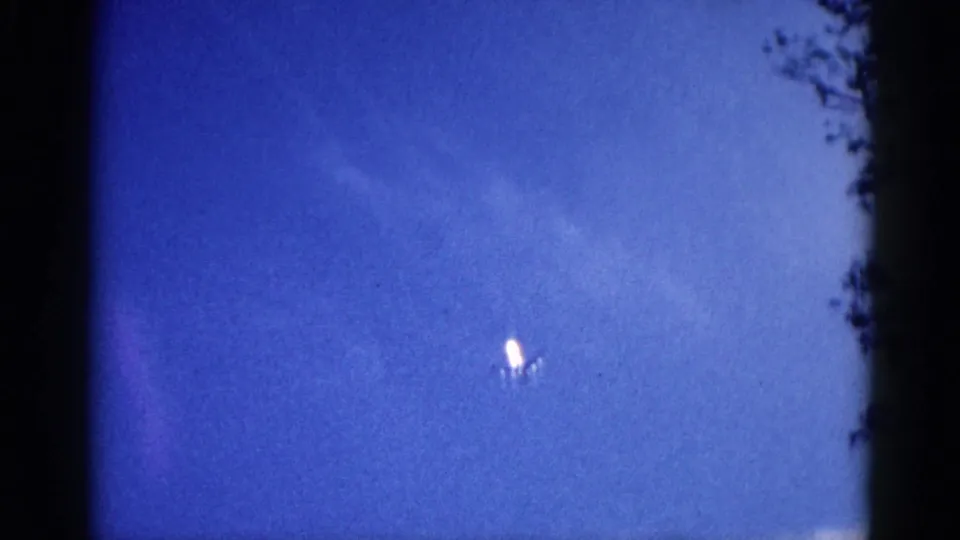 Jet aircraft as luminous white point in saturated blue sky, 8mm home movie, Illinois, circa 1962.