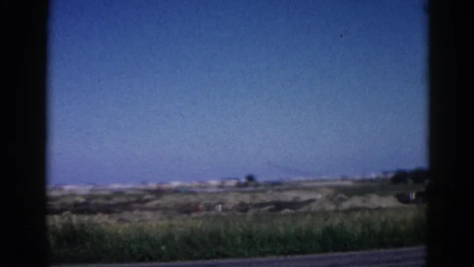 Flat Illinois roadside landscape under open sky, ground-level perspective, 8mm home movie circa 1962.