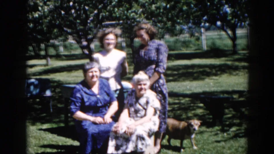 The same four-generation group in an Illinois backyard, c. 1962; a slight camera reframe brings the seated older women into sharper prominence, small dog at right.