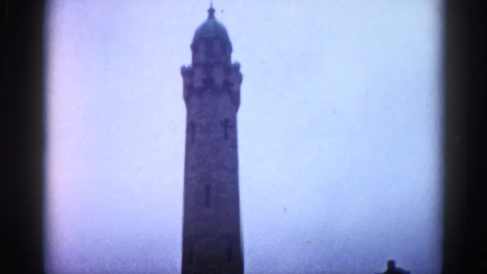Tall stone or masonry civic tower with a decorative domed top, photographed against an overcast sky in Illinois, circa 1962, on 8mm color film.